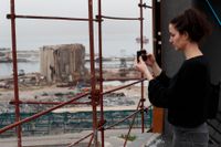 Joana Dagher, 33, som överlevde den våldsamma explosionen i Beirut förra året, tar en bild av hamnen ett halvår efter detonationen.