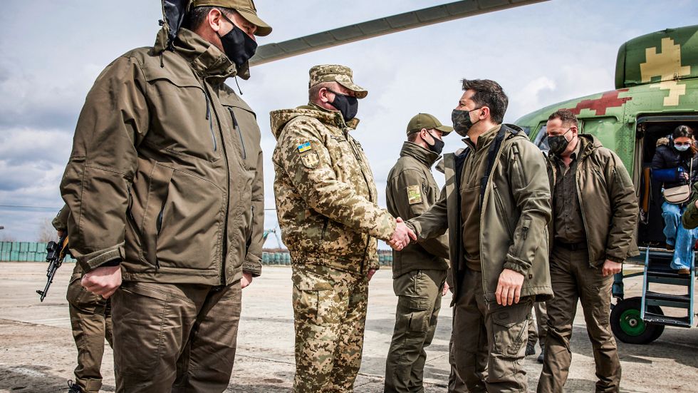 Ukrainas president Volodymyr Zelenskyj skakar hand med en ukrainsk soldat i konfliktområdet i östra Ukraina.