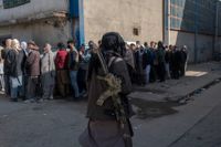 Människor köar för att få ut kontanter vid ett utlämningsställe organiserat av FN:s världslivsmedelsprogram WFP. En taliban övervakar.