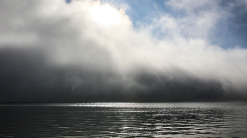 Mörka moln drar in och skymmer solen över stranden på Storön på Norrbottens kust vid Bottenviken.