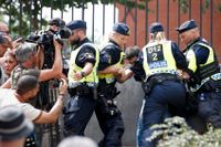 Poliser på plats under koranbränningen utanför Stockholms moské i juni.