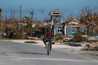 En man cyklar gatan fram i Marsh Harbour som är sargat efter att orkanen Dorian dragit fram.