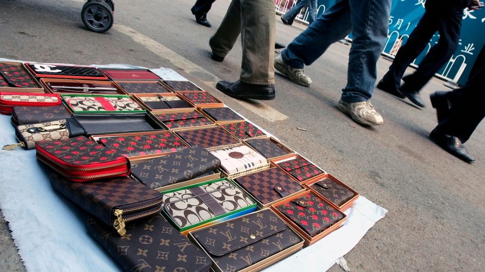 Plånböcker från "Louis Vuitton" till försäljning på en gata. Arkivbild.