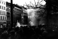 Arkivbild från Kristallnatten i Tyskland den 10 november 1938. Bilden: Stor folksamling i förgrunden och rök som stiger mot skyn en bit längre fram.