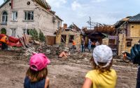 Barn ser på när räddningsarbetare rensar upp vid ett förstört hus i Kramatorsk i östra Ukraina. 