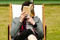 En läsare sitter djupt försjunken i en roman på The Telegraph Hay Festival i Wales. 