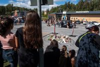Folk samlas vid blommorna och ljusen på rastplatsen där en tolvårig flicka sköts ihjäl vid en bensinmack i Botkyrka, söder om Stockholm natten mot söndagen.
