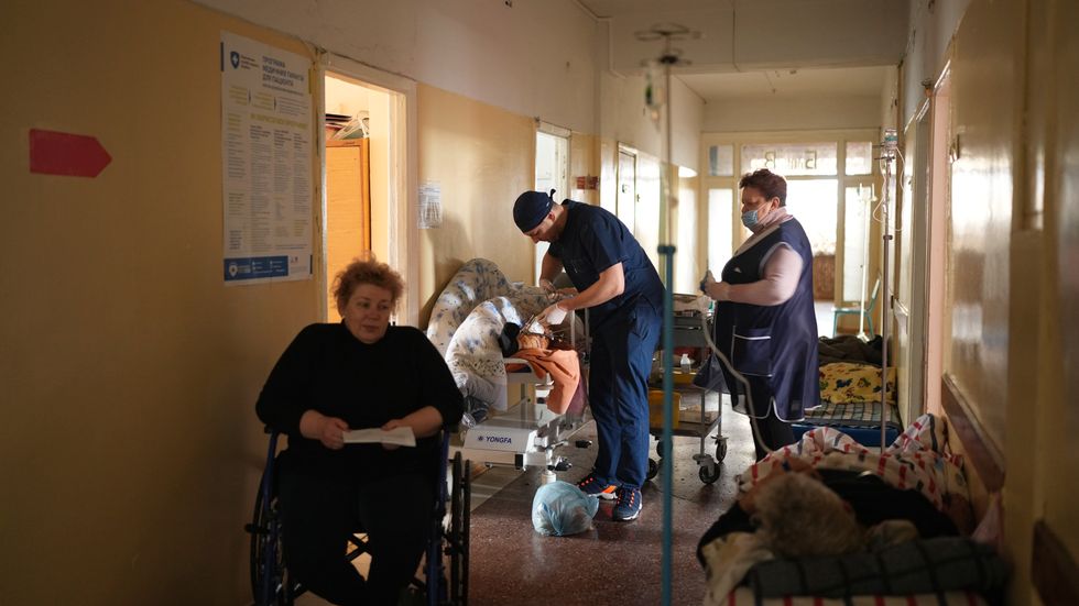 En vårdanställd tar hand om en skadad man på ett sjukhus i Mariupol, en av de ukrainska städer som drabbats hårt av kriget.