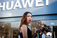 En kvinna använder sin mobil utanför en Huawei-butik i Peking.