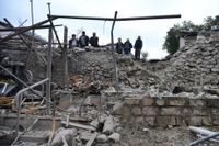 En grupp män granskar rasmassorna som återstår av ett bostadshus i Stepanakert på söndagen.