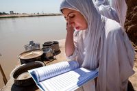 En mandeisk kvinna läser en helg skrift vid floden Tigris.