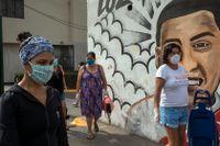 Kvinnor i skyddsmasker köar för att köpa mat på en marknad i Perus huvudstad Lima i lördags.