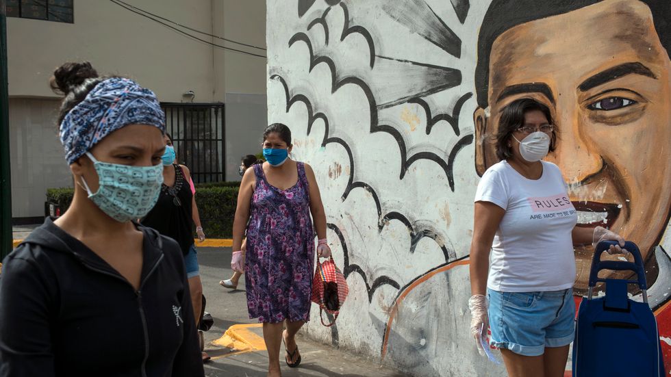 Kvinnor i skyddsmasker köar för att köpa mat på en marknad i Perus huvudstad Lima i lördags.