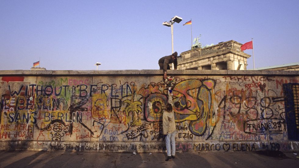 En östtysk gränsvakt får blommor av en västberlinare i samband med att Berlinmuren öppnades. 