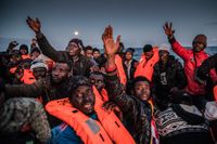 Afrikanska flyktingar tar emot flytvästar från en spansk hjälporganisation i sin gummibåt utanför den libyska kusten.