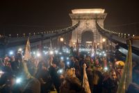 Mobiltelefoner lyser upp ett regeringskritiskt demonstrationståg på Kedjebron i Budapest.