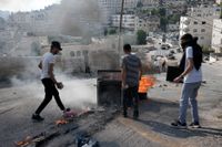Palestinska ungdomar blockerar en väg under sammandrabbningar med israeliska styrkor i Nablus, som sker efter morgonens israeliska luftangrepp.