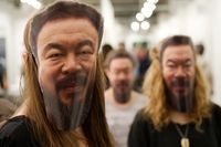 Besökare på konstmässan bär masker föreställande Ai Weiwei.