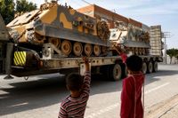 Barn vinkar till turkiska styrkor på väg till syriska gränsen den 15 oktober. 