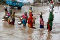 Kvinnor vadar genom en översvämning nära indiska Ahmadabad, Indien. Arkivbild från 2008.