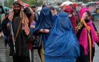 Afghanska kvinnor flankerade av beväpnade talibaner på en marknad i Kabul i maj.