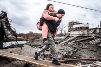 En man bär en kvinna på sin rygg i Irpin, i närheten av Kiev.