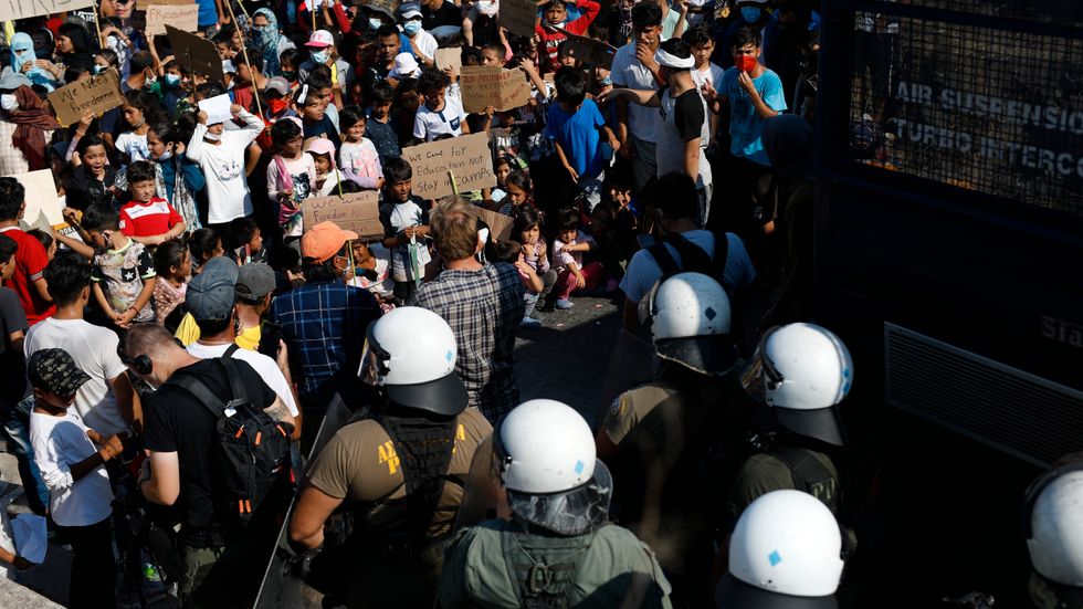 Poliser blockerar en väg nära Mytilene på Lesbos, där migranter protesterar.