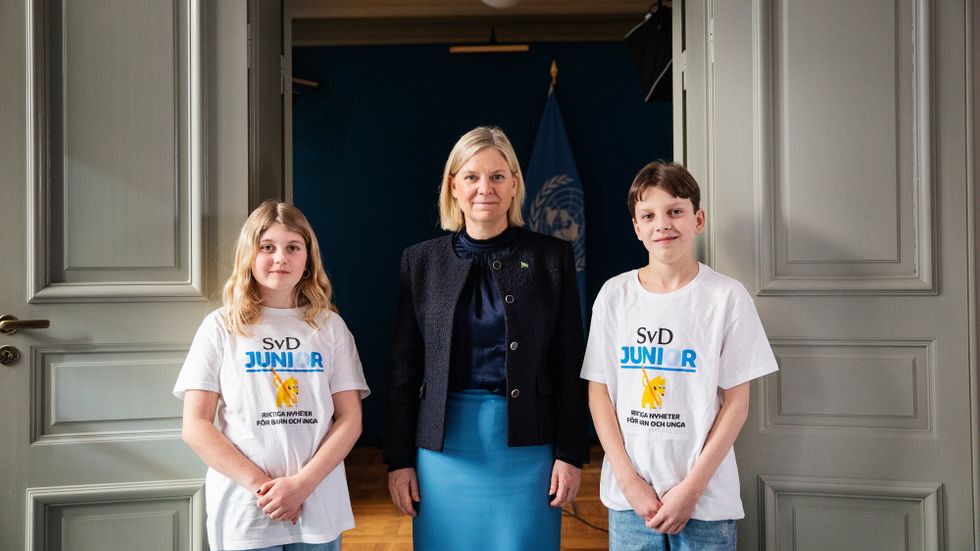 ”Äntligen är jag längst. Jag brukar alltid vara kortast”, skojar statsministern Magdalena Andersson när hon fotas tillsammans med juniorreportrarna Doris, 10, och William, 12.