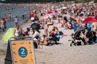 En skylt påminner om att hålla avstånd på stranden i Lomma, Skåne. Polisen i Sverige har fått in många samtal om trängsel på badstränder.