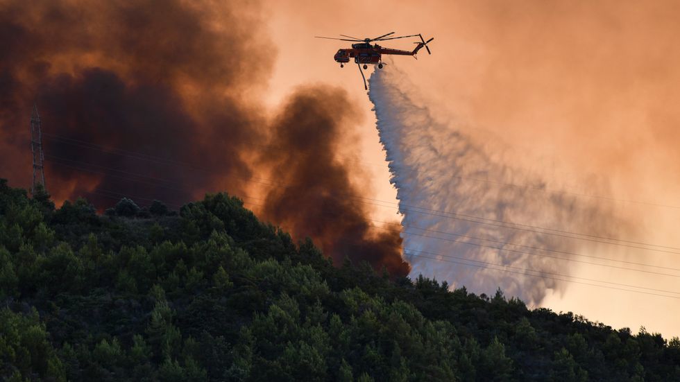 En helikopter deltar i släckningsarbetet vid byn Krestena, 32 mil sydväst om Aten, på söndagen.