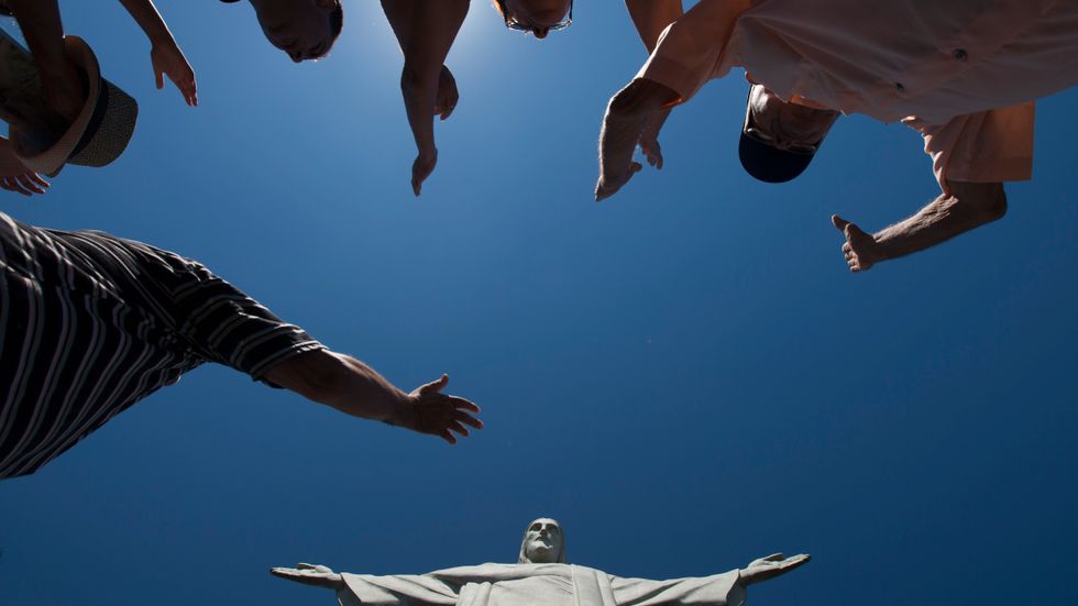 Besökare lyfter sina händer vid Kristusstatyn i Rio de Janeiro, Brasilien.