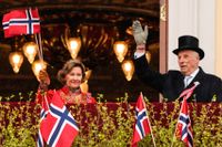 Norska kungaparet vinkar från slottsbalkongen under nationaldagsfirandet 2021.