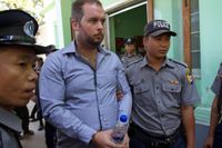 Barägaren Philip Blackwood eskorteras till rätten av polis. Tillsammans med två burmeser står han åtalad för att ha ”förolämpat religionen”.