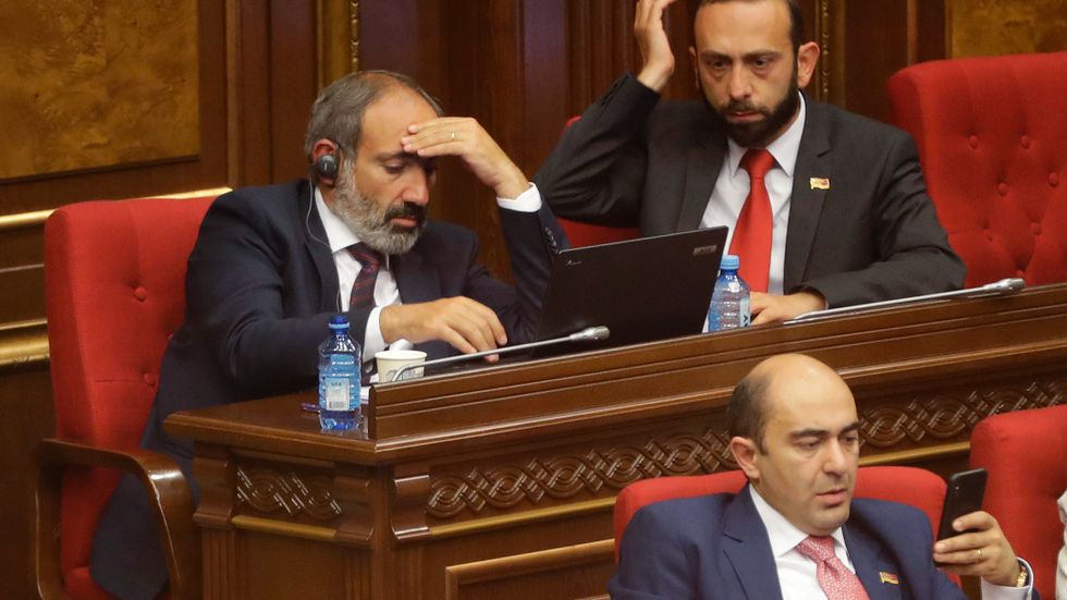 Premiärminister Nikol Pasjinjan, till vänster, tar sig för pannan under ett tidigare sammanträde i parlamentet. Arkivbild.