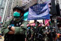 Polis håller i en skylt som varnar för att det är olagligt att protestera i Hongkong.