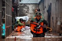 Kinesisk polis hjälper till med evakueringar i områden drabbade av översvämningar. Bilden har distribuerats av den statligt styrda nyhetsbyrån Nya Kina.