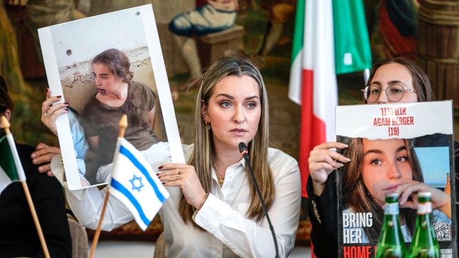 Ashley Waxman Bakshi håller upp ett foto  på sin kusin Agam Berger som togs som gisslan av Hamas den 7 oktober. Till höger Bergers syster Li-Yam. Bilden är från Rom i förra veckan.