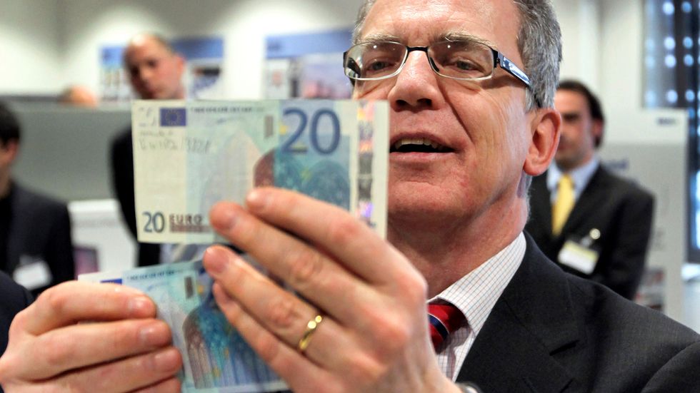 Tysklands förre inrikesminister Thomas de Maizière studerar eurosedlar. Arkivbild.