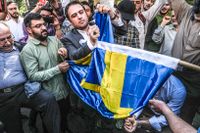 Demonstranter bränner en svensk flagga framför svenska ambassaden i Irans huvudstad Teheran i fredags