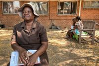 Regina Mangama är lekmannaterapeut och hjälper klienter med psykisk ohälsa på en bänk utanför Budiriro vårdcentral nära Harare, Zimbabwe.