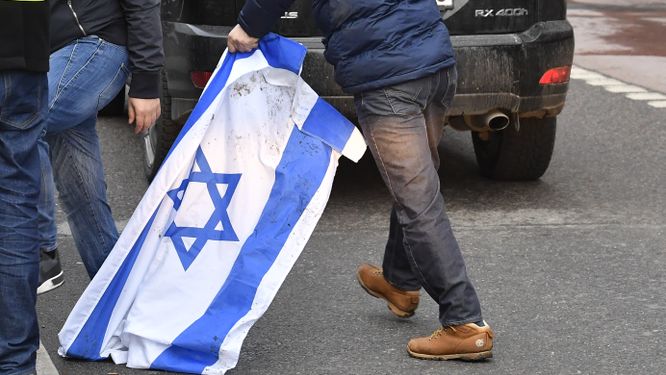 Propalestinska demonstranter trampar på en israelisk flagga.
