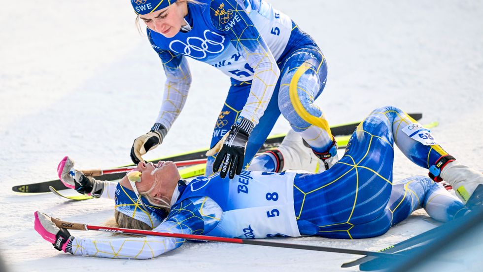 Sveriges Frida karlsson får hjälp av landslagskompisen Ebba Andersson efter på 10 km klassisk stil under vinter-OS i Peking.