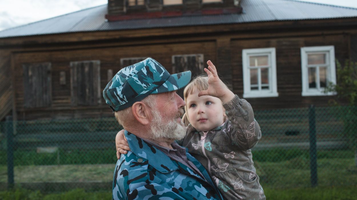 Vladimir Ritjkov, 68 år, med sitt barnbarn i byn Medvedevo, fem personer bor där året om. Han är från Totma, den tredje klockmästaren i familjen. ”Floden var en knutpunkt. Klart att jag känner nostalgi. Vardagen fungerade. Det fanns kvalitetsprodukter i affärerna”.