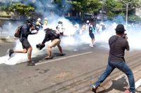Polis skjuter tårgas mot demonstranter i Myanmars största stad Rangoon under måndagen.