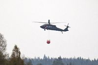 En helikopter vattenbombar skogsbranden i skånska Hästveda. En skogsbrand rasar i Hästveda i Hässleholms kommun och flera familjehus har utrymts.