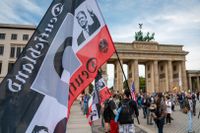 En demonstrant håller en tysk riksflagga med en bild på Donald Trump framför Brandenburger Tor i Berlin.