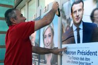 En kampanjarbetare sätter upp affischer på Emmanuel Macron.
