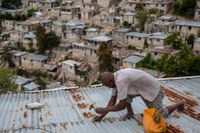 En man i Port-au-Prince i Haiti, stormsäkrar sitt hus i väntan på det tropiska ovädret Elsa.