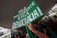 Miljöaktivister håller upp skyltar med orden "För miljö och för demokrati" under en protest i Brasiliens huvudstad Brasilia mot presidentkandidaten Jair Bolsonaro, vars klimatpolitik får kraftig kritik. Bilden är från 19 oktober.