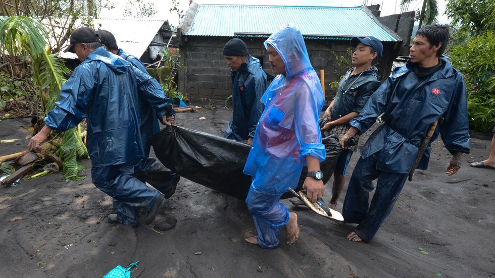 Räddningsarbetare bär en man som drunknade när tyfonen Goni drog fram över Guinobatan i den filippinska provinsen Albay.